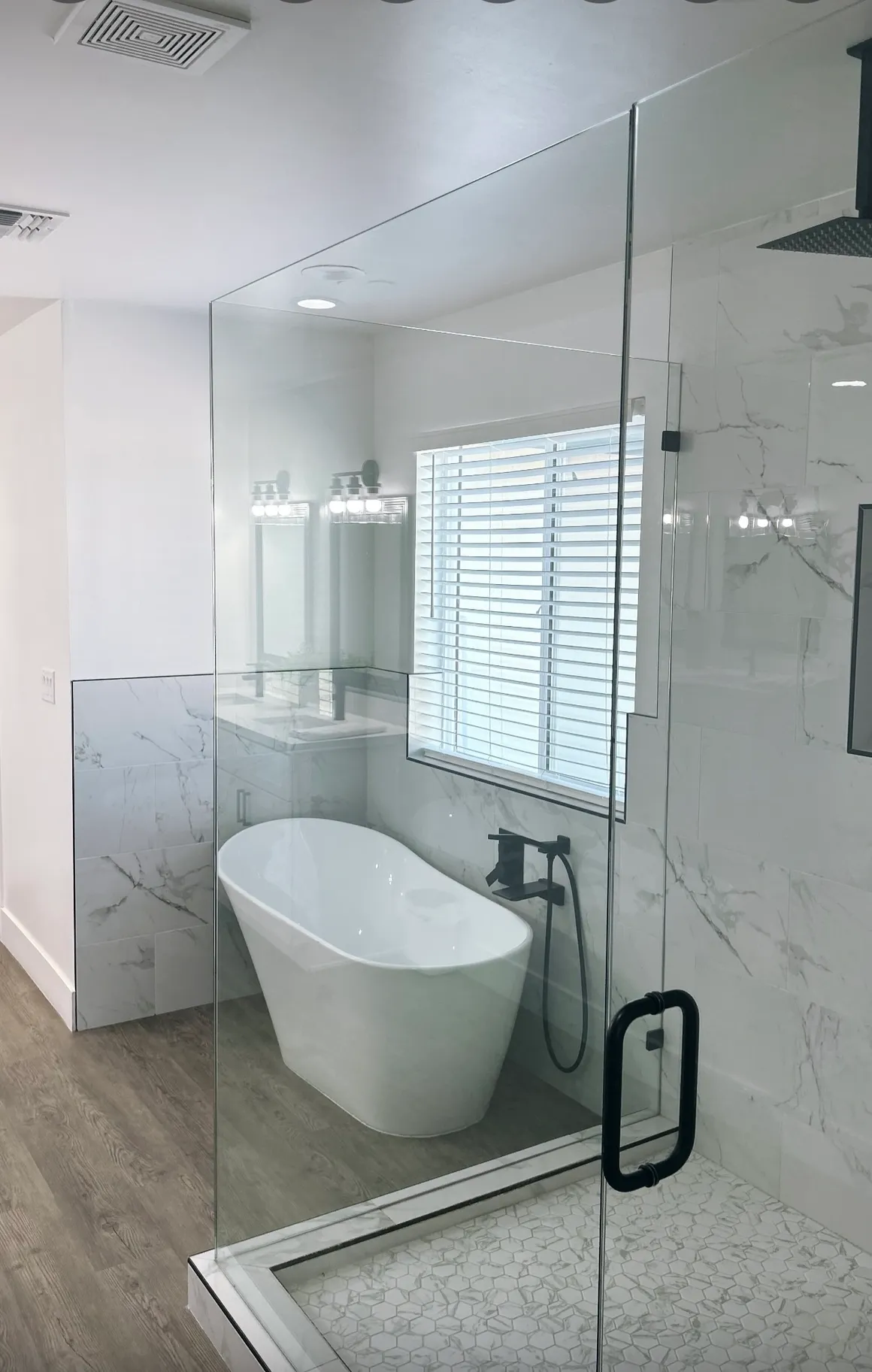 Luxury bathroom with freestanding soaking tub, marble tile, and glass shower enclosure